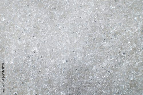 Macro shot of white sugar closeup on the surface as an abstract background. Food industry benefits and harms of granulated sugar