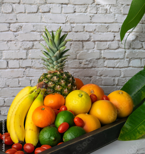 Fruit medley on a tray against a white brick background.