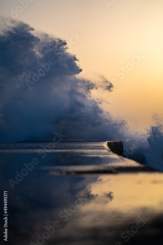 Close-up shot of a pier under the wave splashes during the sunset in Pontao Praia do Tamariz photo