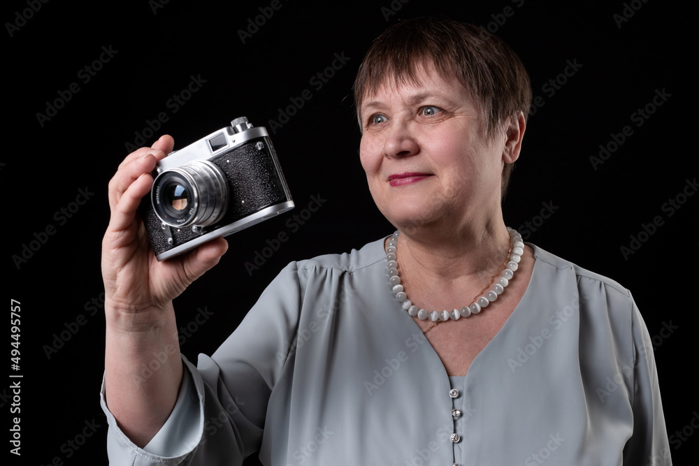 Fototapeta premium An elderly woman holds an old camera in her hands.