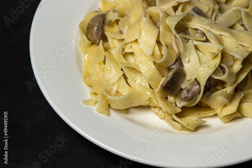 Italian pasta with mushrooms on a black background. Traditional home cooking.