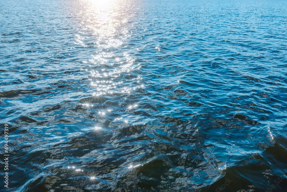 Wonderful natural blue water sun light reflects make sparkles in the sunset evening water.