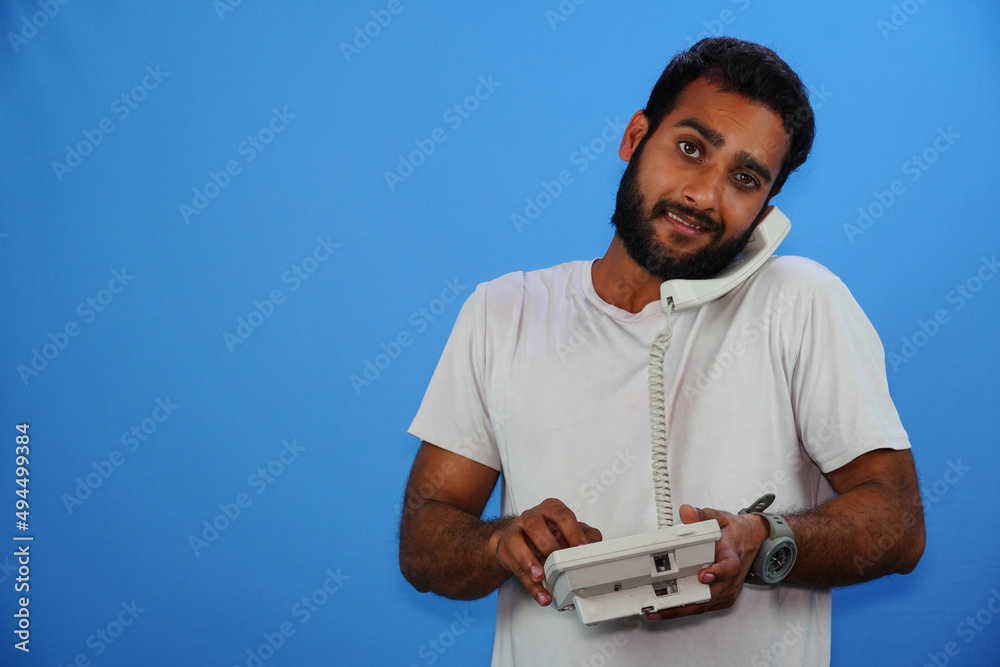 handsome young man talking by telephone on blue background