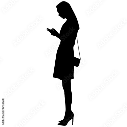 Black silhouette of slender woman in short dress with purse in high-heeled shoes in phone in her hand
