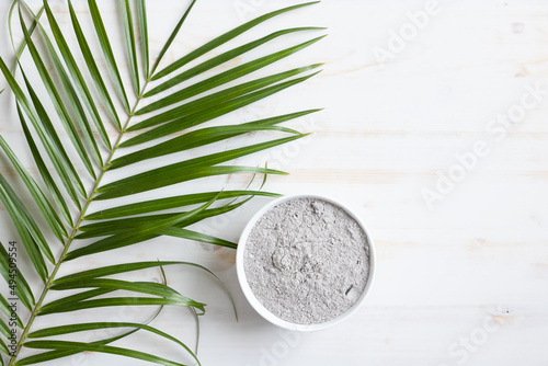 bowl of ashes and palm branch on white wood background photo
