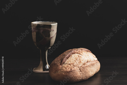 Clay chalice with a loaf of artisan bread on a black background