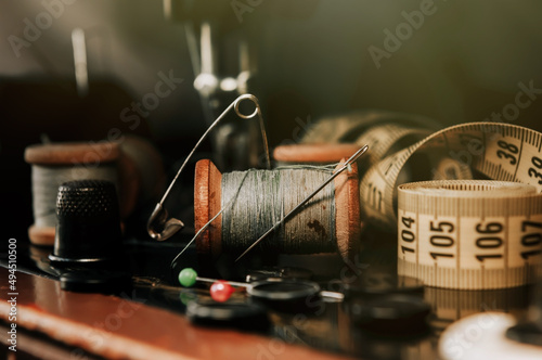 Old retro tailor's tools for sewing clothes. Centimeter, scissors, thimble and needle with snitch.