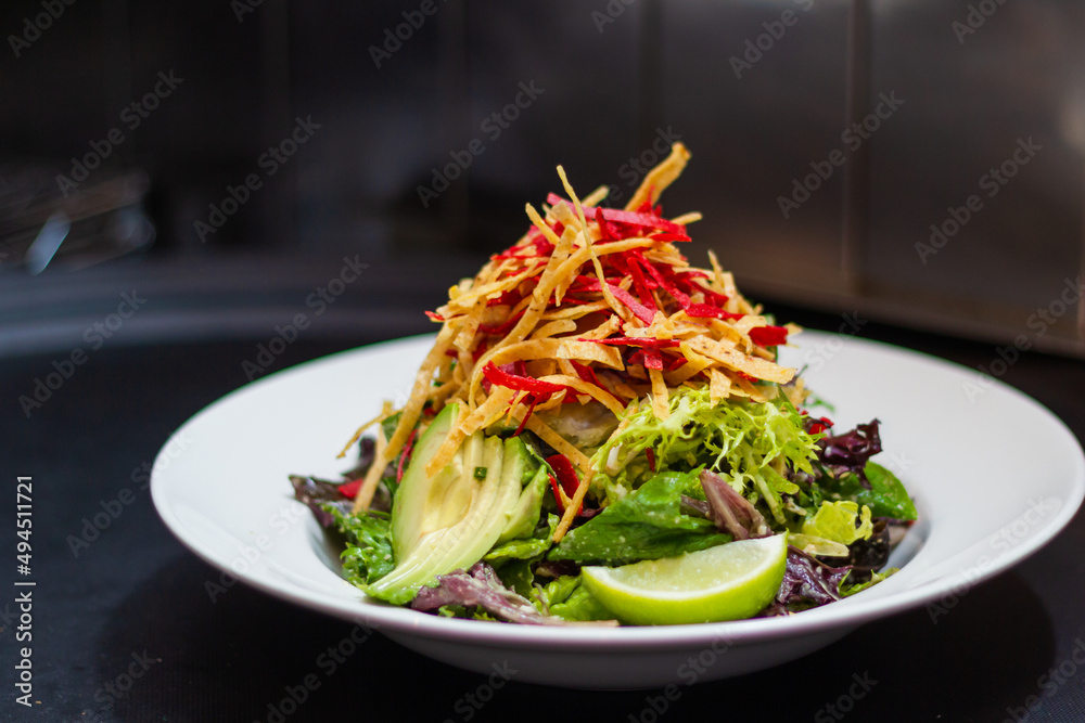 Obraz premium Santa Fe salad tossed in creamy peanut lime dressing topped with tortilla chips and lime wedge
