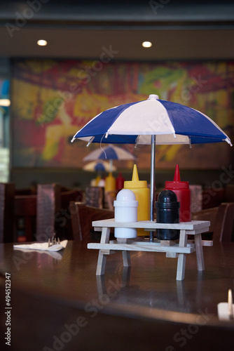Sauce stand with an umbrella on a restaurant table photo