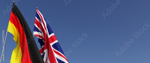 Flags of Germany and United Kingdom on flagpoles on the side. Flags on a blue background. Place for text. Berlin, Munich. England, Britain. Commonwealth. 3D illustration.