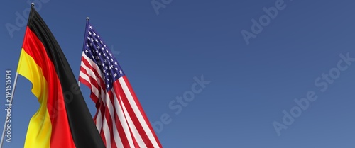 Flags of Germany and the United States of America on flagpoles on side. Flags on a blue background. Place for text. Berlin, Munich. Washington. Commonwealth. 3D illustration.