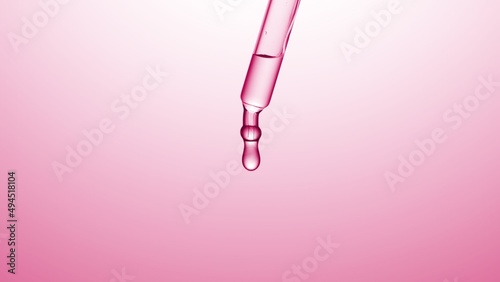Macro shot of drop hanging from chemical dropper on pale pink background | Abstract skincare lotion ingredients formulating concept photo