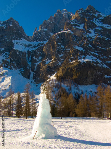 Vertical shot of snow hill in the shape of a wolf on a background of a snow-covered mountain, Italy