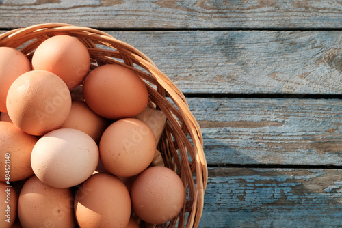 Large brown eggs in a basket. Blue wooden background for text. Dietary farm product. Copyspace.