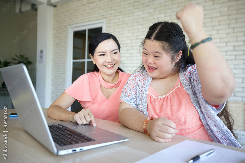 down syndrome teenage girl and her teacher studying how to use laptop computer for education, and raised arm pose in success