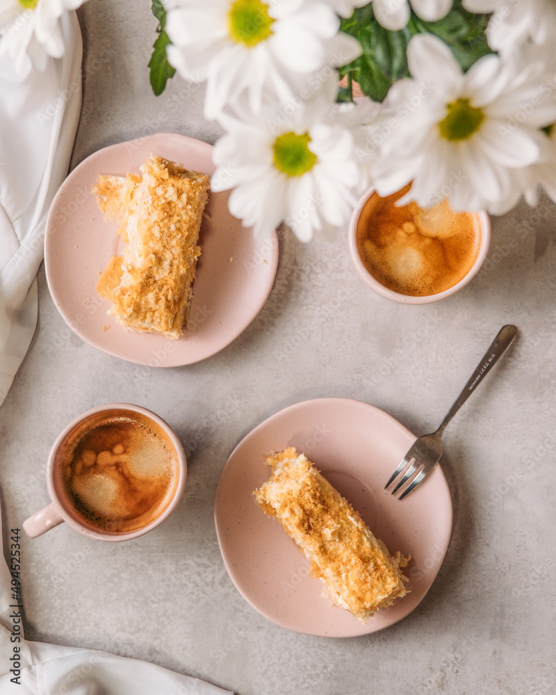cup of coffee and piece of Napoleon Cake and white flowers cup of coffee and piece of Napoleon Cake and white flowers