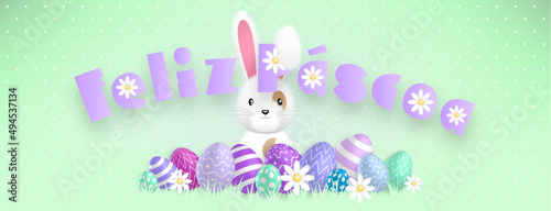 Spanish purple text : Feliz Pascoa, with a cute white bunny behind colored eggs and flowers on a green background