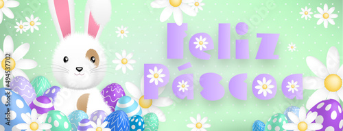 Spanish purple text : Feliz Pascoa, with a cute white rabbit behind colored eggs and flowers on a green background