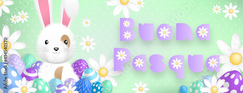 Italian purple text : Buona Pasqua, with a cute white rabbit behind colored eggs and flowers on a green background