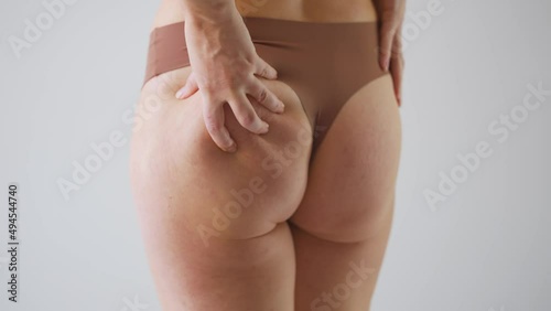 Woman compressing the skin on her buttocks checking for cellulite and excess subcutaneous fat photo