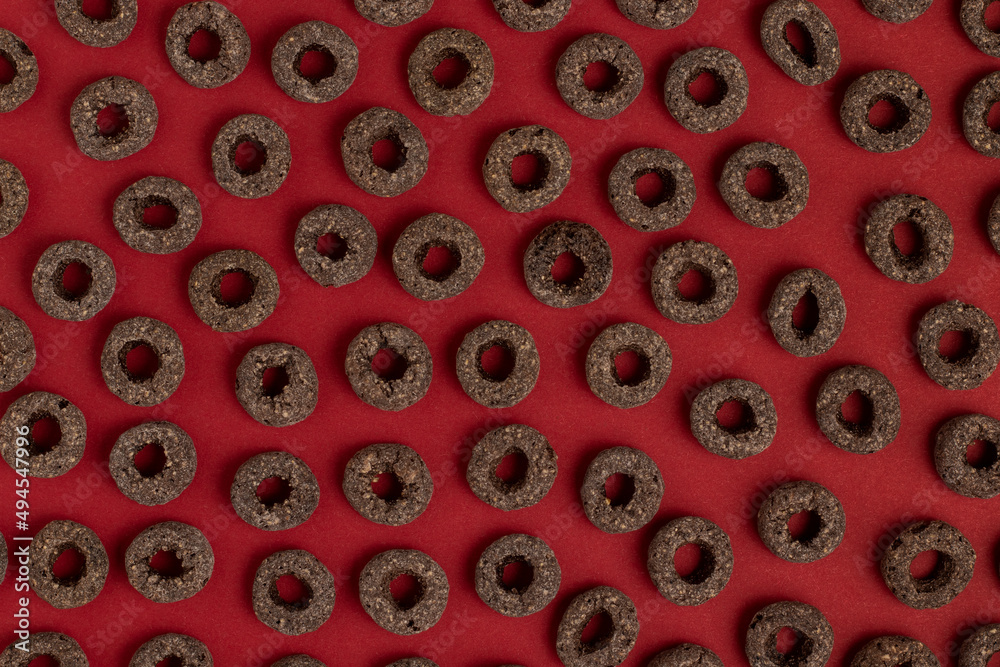 Breakfast cereal. Round black flakes on a red background. Breakfast cereal. Round black flakes on a red background.