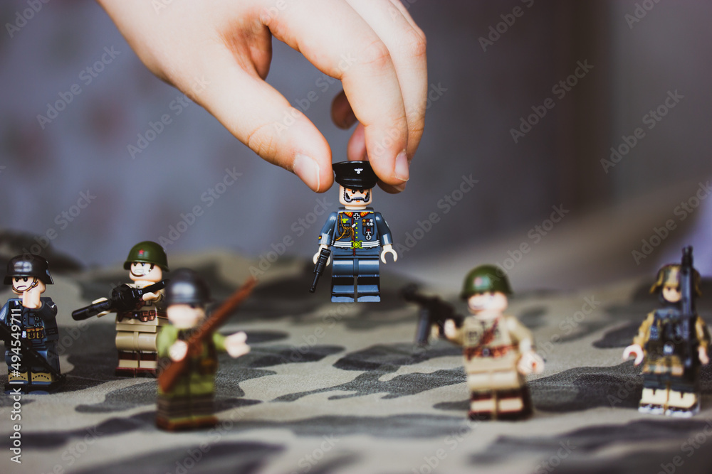 Kyiv, Ukraine. March 9, 2022. Figurine of officer in child's hand. A kid  plays LEGO soldiers
