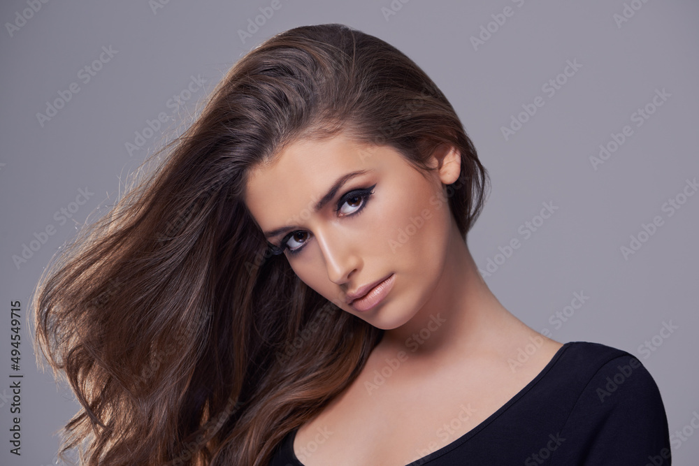 She exudes feminine beauty. Studio portrait of a gorgeous young woman against a gray background. She exudes feminine beauty. Studio portrait of a gorgeous young woman against a gray background.
