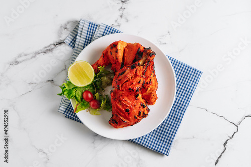 indian culture Tandoori chicken with lime in a dish isolated on napkin side view on grey background photo