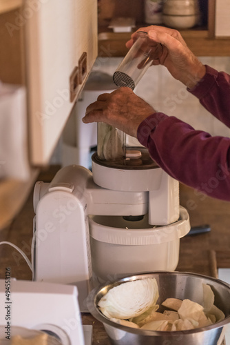 Alter Mann Opa mit Hände benutzt eine Küchemasche und schneidet häckselt Weißkohl für einen Salat in einer Küche, Deutschland
