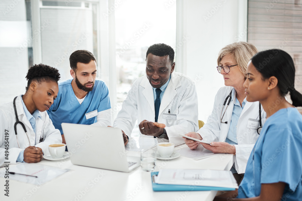 Working together for their patients. Shot of a group of medical practitioners using a laptop during a meeting in a hospital boardroom. Working together for their patients. Shot of a group of medical practitioners using a laptop during a meeting in a hospital boardroom.
