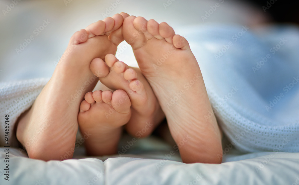 Your tiny toes and mine. Cropped shot of a parent and childs feet sticking out under covers. Your tiny toes and mine. Cropped shot of a parent and childs feet sticking out under covers.