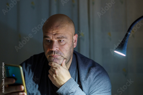 Middle-aged man with a serious face looking at the phone. 
