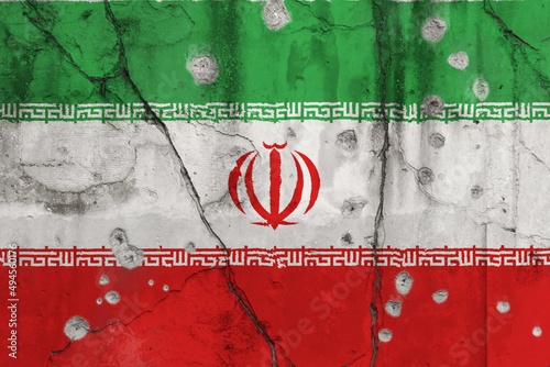 Full frame photo of a weathered flag of Iran painted on a cracked wall with bullet holes. Violence in Iran concept.