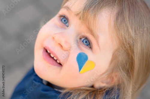 portrait of a girl with a blue and yellow heart on the cheek  photo
