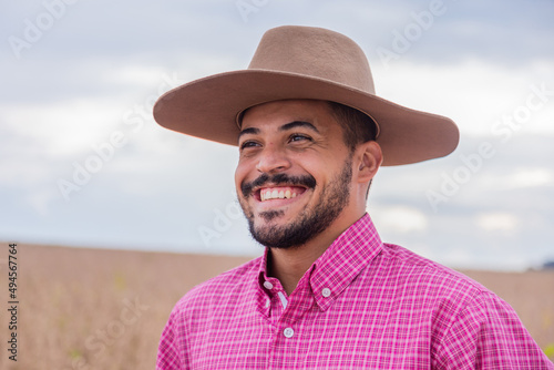 Portrait of smiling beautiful young male farmer. Man at farm in summer day. Gardening activity. Brazilian man.