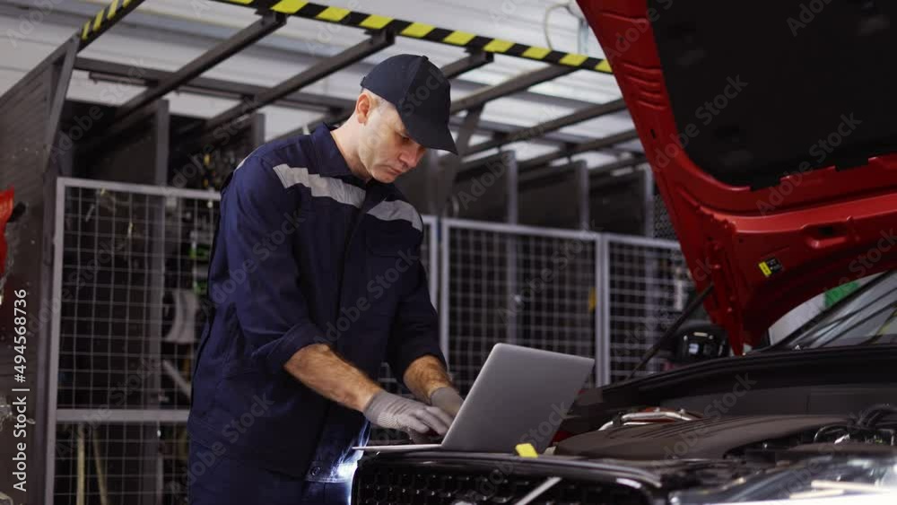Auto mechanic uses a laptop while conducting diagnostics test Auto mechanic uses a laptop while conducting diagnostics test
