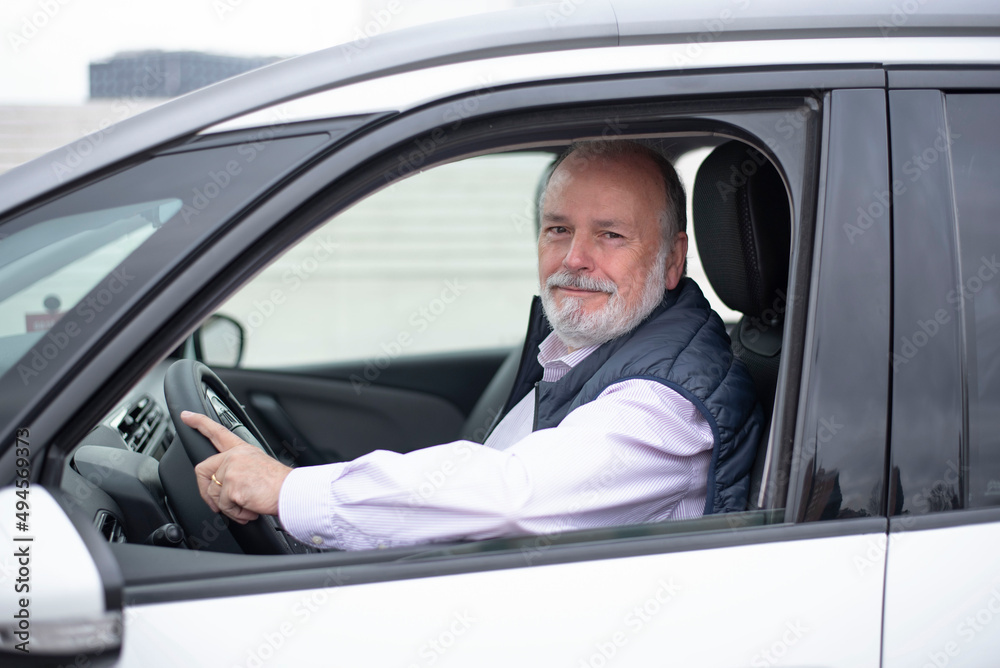 portrait of an elderly driver in car or taxi