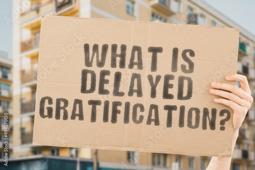 Billede på lærred The question  What is delayed gratification?  on a banner in men's hands with blurred background