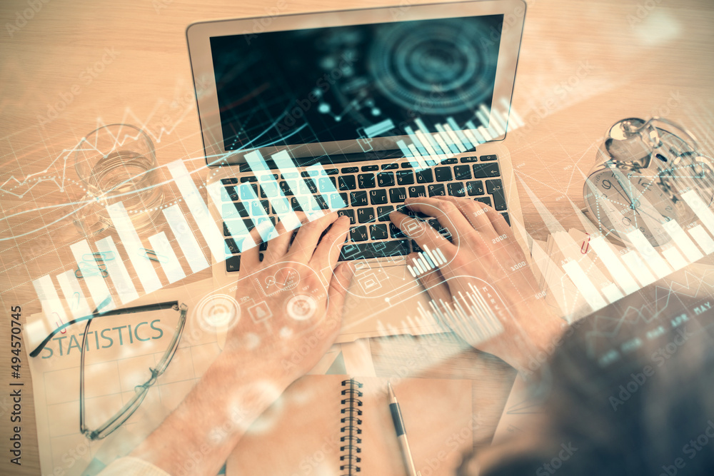 Double exposure of man's hands typing over laptop keyboard and forex chart hologram drawing. Top view. Financial markets concept.