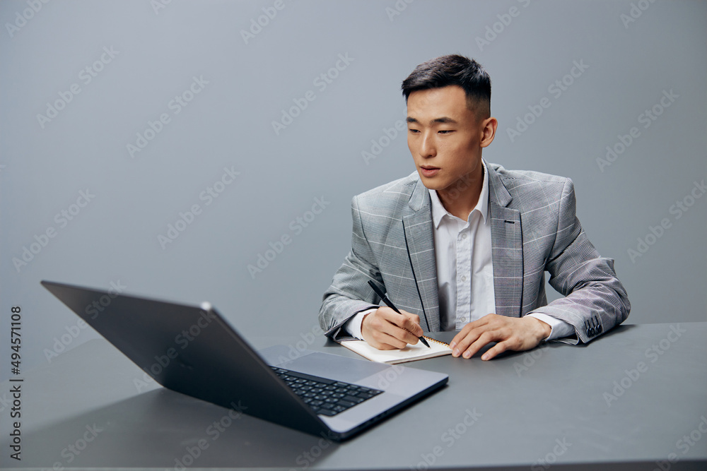 man sitting at a desk in front of a laptop work writing in a notebook executive man sitting at a desk in front of a laptop work writing in a notebook executive