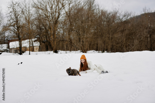 Happy young woman winter clothes walking the dog in the snow Lifestyle