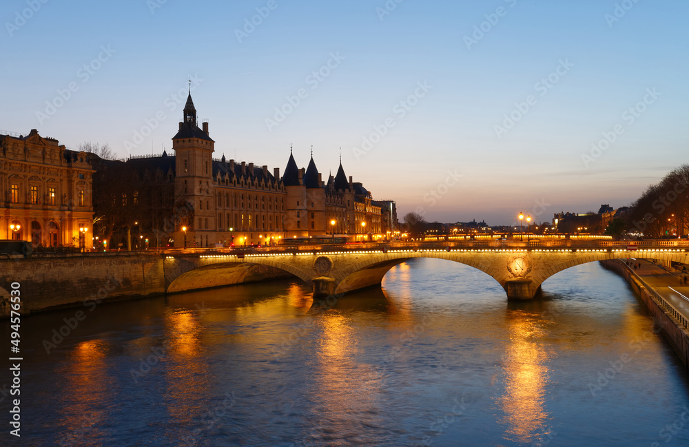 Panorama of Conciergerie and Illuminated bridge Pont au Change at night, Paris.