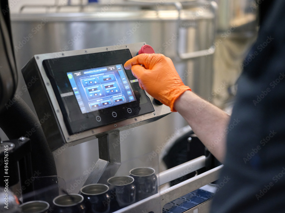 Worker operating an electronic beer filling machine in a brewery