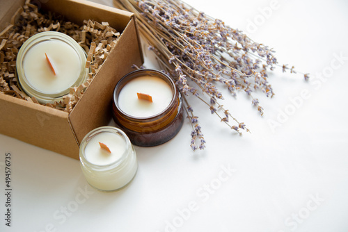 An open box with candles on a white background, next to it are several candles in a jar and a dried bouquet of lavender. High quality photo photo