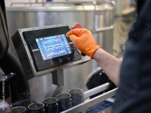 Worker operating an electronic beer filling machine in a brewery