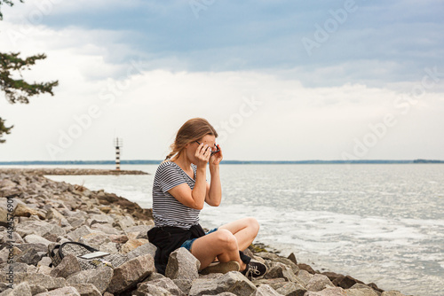 Beautiful girl on the sea overlooking the lighthouse and blue sky with clouds © Minakryn Ruslan 