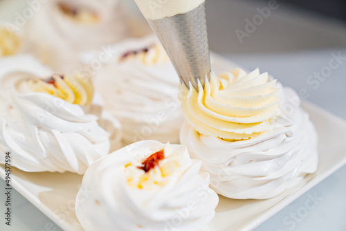 chef decorates with cream to Anna Pavlova cakes in kitchen photo