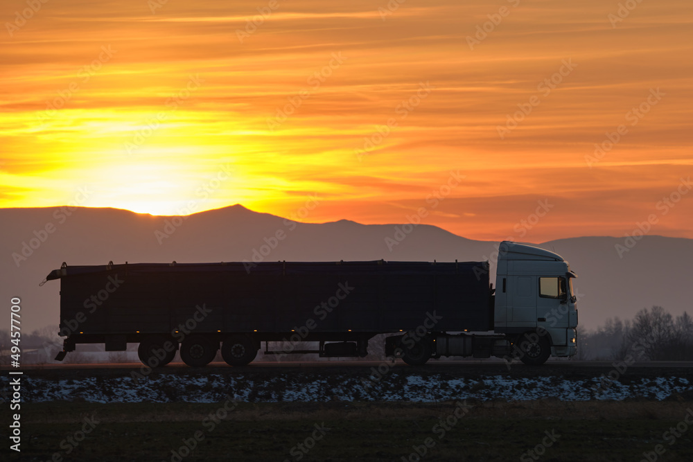 Semi-truck with cargo trailer driving on highway hauling goods in evening. Delivery transportation and logistics concept Semi-truck with cargo trailer driving on highway hauling goods in evening. Delivery transportation and logistics concept