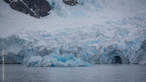 Gigantisch, ein riesiger Gletscher bestehend aus blau weißem Eis ergießt sich in den antarktischen Ozean, dabei brechen große Eisberge ab, welche im blauen Wasser treiben photo