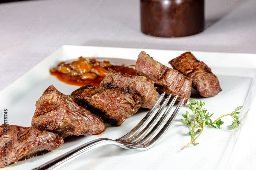 Beef kebab with tomato sauce with vegetables is on a plate Beef kebab with tomato sauce with vegetables is on a plate